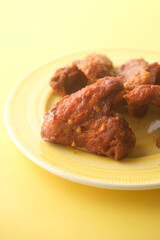 chicken wings in a plate on yellow background 