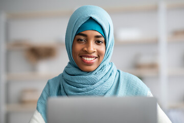 Closeup Portrait Of Black Islamic Freelancer Lady In Hijab Using Laptop