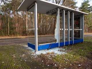 Vandalised Broken bus stop in the city. Dangerous,  crashed tempered glass pieces on ground
