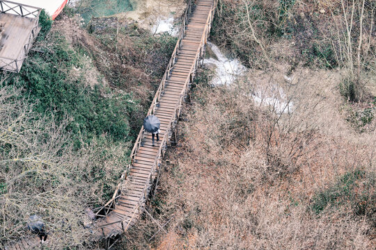 Aerial view, during rainy day, people carry umbrella, people walking on wooden bridge and walking on bridge.