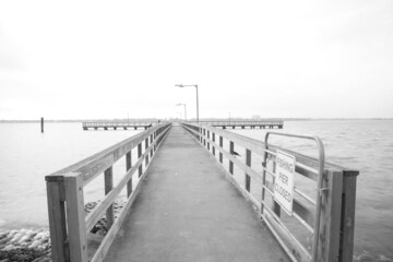 Obraz premium Black and White view fishing pier with gate and sign stretching out Clear Lake near Seabrook, Greater Houston, Texas, USA