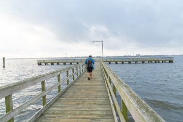 Unidentified angler walking on wooden fishing pier stretching out Clear Lake near Seabrook, Greater...