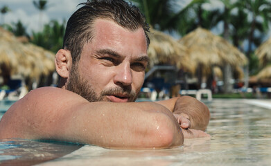 Handsome wrestler sportsman with Cauliflower ears relaxes in the swimming pool, recovery after hard training. 