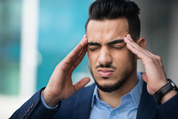 Stressed young arab businessman suffering from headache