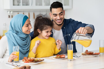 Healthy Drink. Happy Arab Father Pouring Orange Juice For Daughter And Wife
