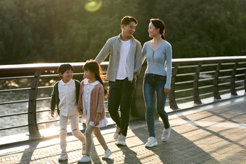 asian family with two children taking a walk in city park
