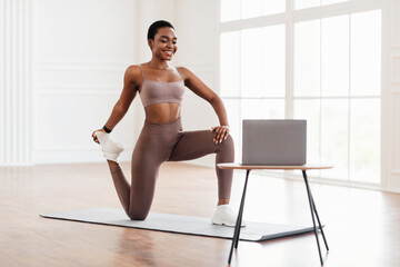 Smiling African Woman In Sportswear Doing Legs Quad Stretching Exercise