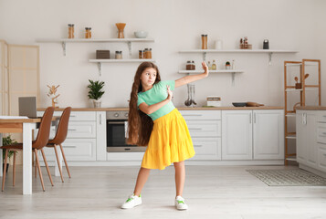 Cute little girl in yellow skirt dancing in kitchen