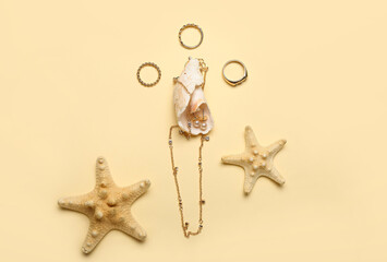 Fototapeta na wymiar Stylish golden jewelry, seashells and starfishes on color background