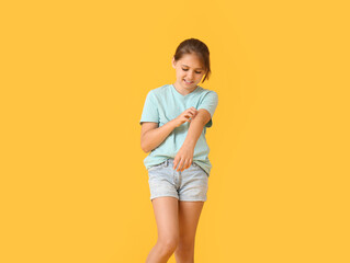 Little girl scratching herself on color background
