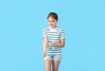 Little girl with mosquito repellent on color background