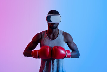 Strong black sportsman in VR headset putting boxing gloves together in neon light