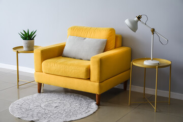 Interior of light living room with yellow armchair, lamp and coffee tables