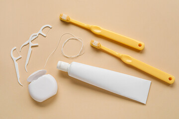 Dental floss, toothpicks, brushes and paste on beige background