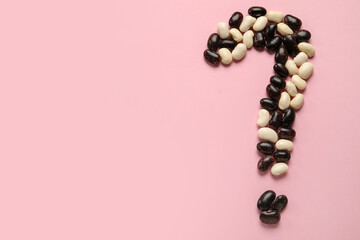 Question mark made of raw beans on pink background