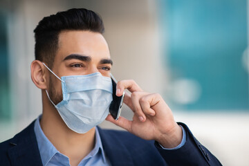Arab businessman in medical face mask talking on phone