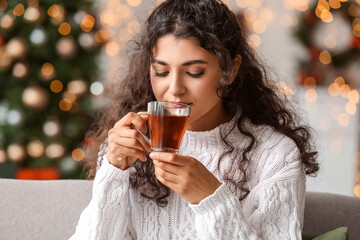 Beautiful woman drinking tea at home on Christmas eve