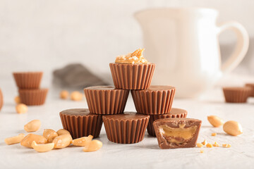 Tasty peanut butter cups on light background