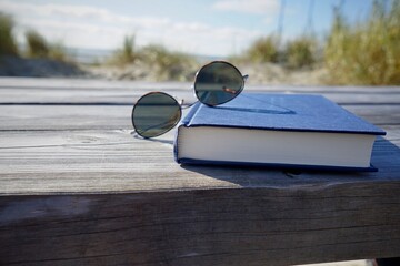 Fototapeta na wymiar Book and sunglasses in the dunes