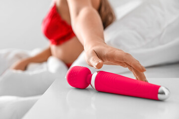 Young woman taking vibrator from bedside table