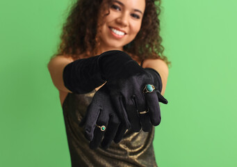 Elegant young woman with stylish gloves on color background, closeup