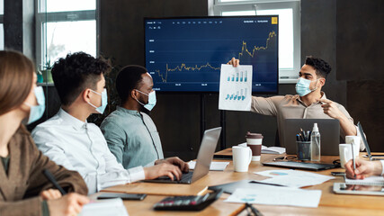 Man in protective medical mask showing paper with graph diagram