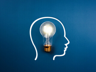 Creative idea, innovation, knowledge, and inspiration concept. The human head icon and gears and cogs work inside the light bulb with network connection symbol on the blue background, minimal style.