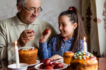 happy grandfather and granddaughter hold easter eggs in hand, folk game beats easter egg