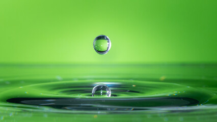 Water drop falling and impacting body of water.