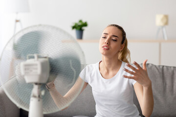 Mature woman cooling herself in front of fan during hot weather