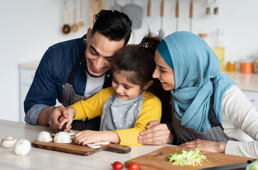 Obraz na płótnie Canvas Loving Muslim Parents Teaching Cute Little Girl How To Cook