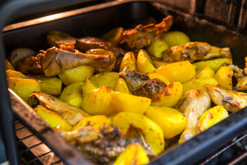 Potatoes with chicken meat in the oven on a tray, side view