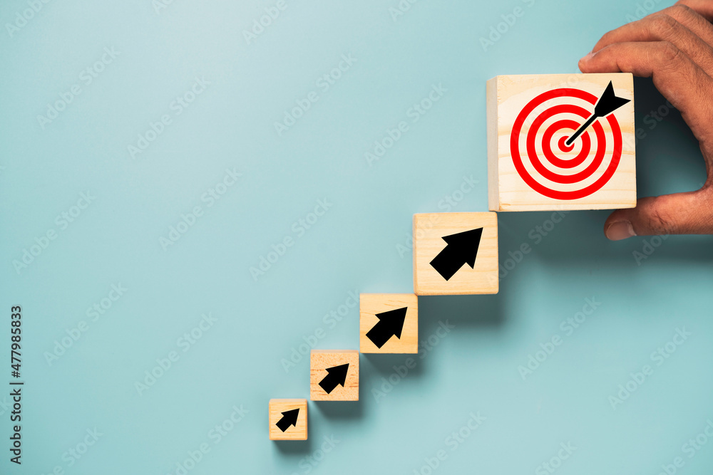 Poster hand putting virtual target board and arrow which print screen on wooden cube. business achievement 