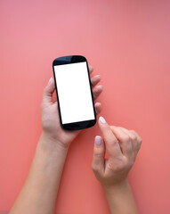 Women's hands hold the phone. Minimalistic layout on a pink background with copy space.