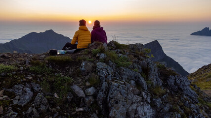 Midnight sunset view with two people in the mountains in Norway