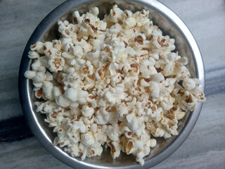 Popcorn in a steel pot. the pot is on the floor.