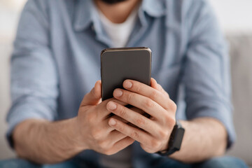 Closeup of smartphone in male hands, guy surfing internet online, selective focus. Gadgets, mobile applications concept.