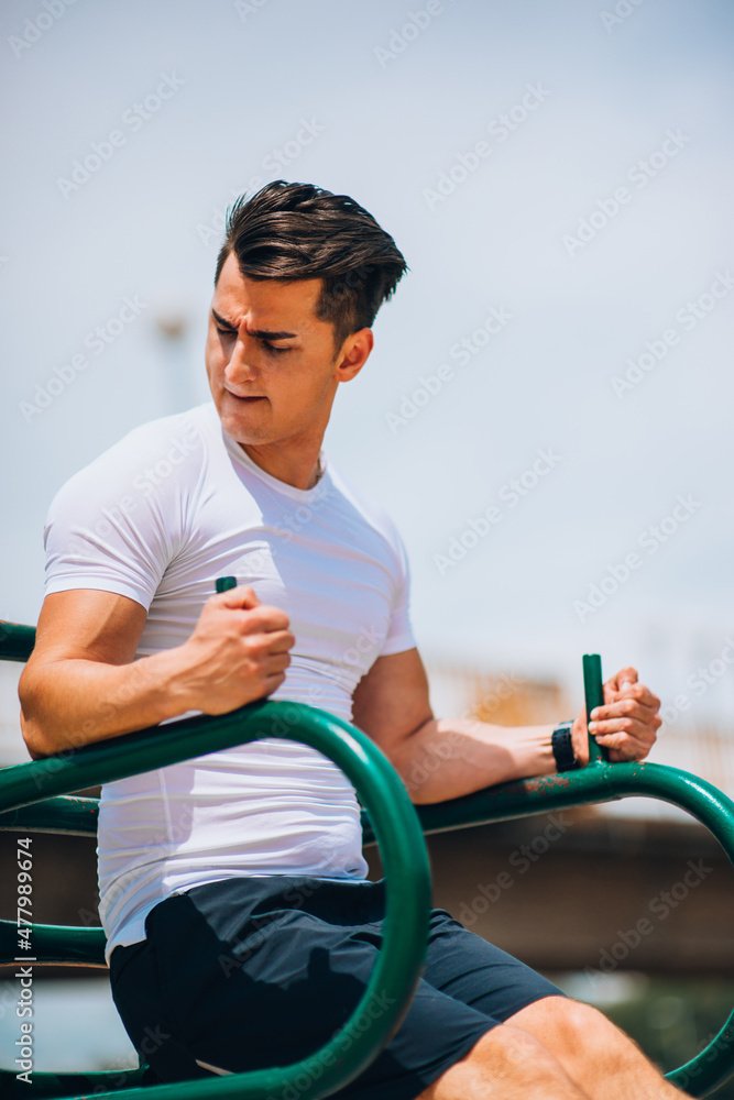 Wall mural Sportive man exercising abdominal muscles on bar