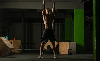 Fit man throwing medicine ball doing ball slam against gym floor or shoulder press exercise..