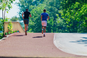 Rearview of two male friends running outdoors in a park