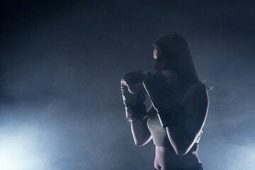 Side view of a silhouette young woman with boxing gloves making a direct hit.