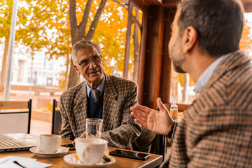 Having a serious discussion in the cafe while sitting and drinking coffee on their meeting, outside