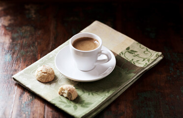 Cup of coffee with amaretti (Italian biscuits) on rustic wooden background.