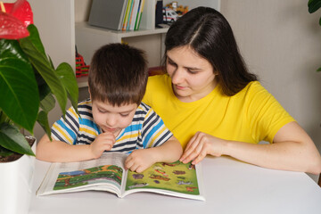 Mother and son read the book, look at the pictures on the pages. Leisure for children, spending time with parents.