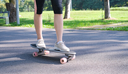 Young teen girl learning to rides a skateboard. Young woman learning skateboarding lesson in the park. Portrait of young female skateboarding in the park. Woman standing and learning to ride skate.