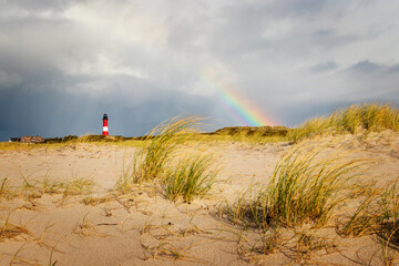 Rainy dune landscape with lighthouse and rainbow at Hörnum, Sylt - North sea nature with special...
