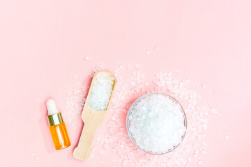 natural sea salt in glass bowl and wooden spoon isolated on beige pink