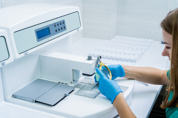 Laboratory assistant works at paraffin wax dispenser tissue embedding machine.