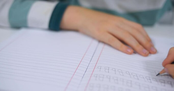 School boy practicing writing the alphabet at home. Boy child kid writing. Homework.