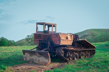 Agricultural machinery in the meadow. Farming machinery for cultivating the land. Old tractor.